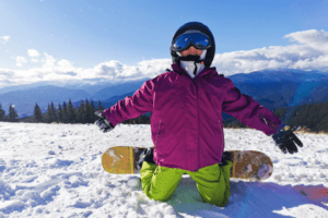 Snowboarderin liegt glücklich im schnee im Ski Ferienlager