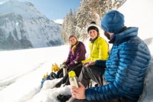 drei Persoenen machen im Schnee eine Pause