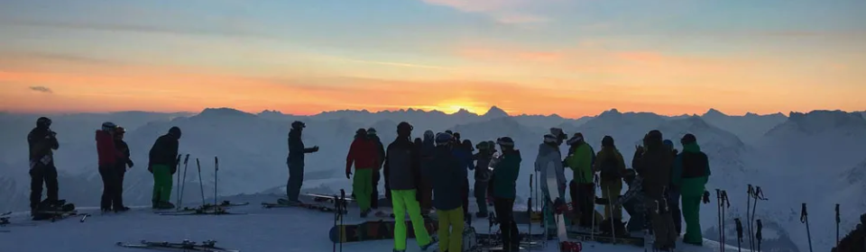 Viele Skifahrer bei Sonnenuntergang auf dem Berg